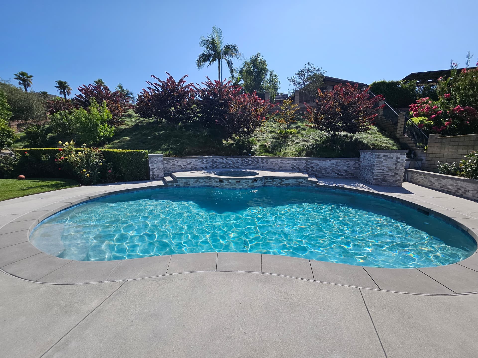 Remodeled kidney shaped pool with raised stacked stone spa