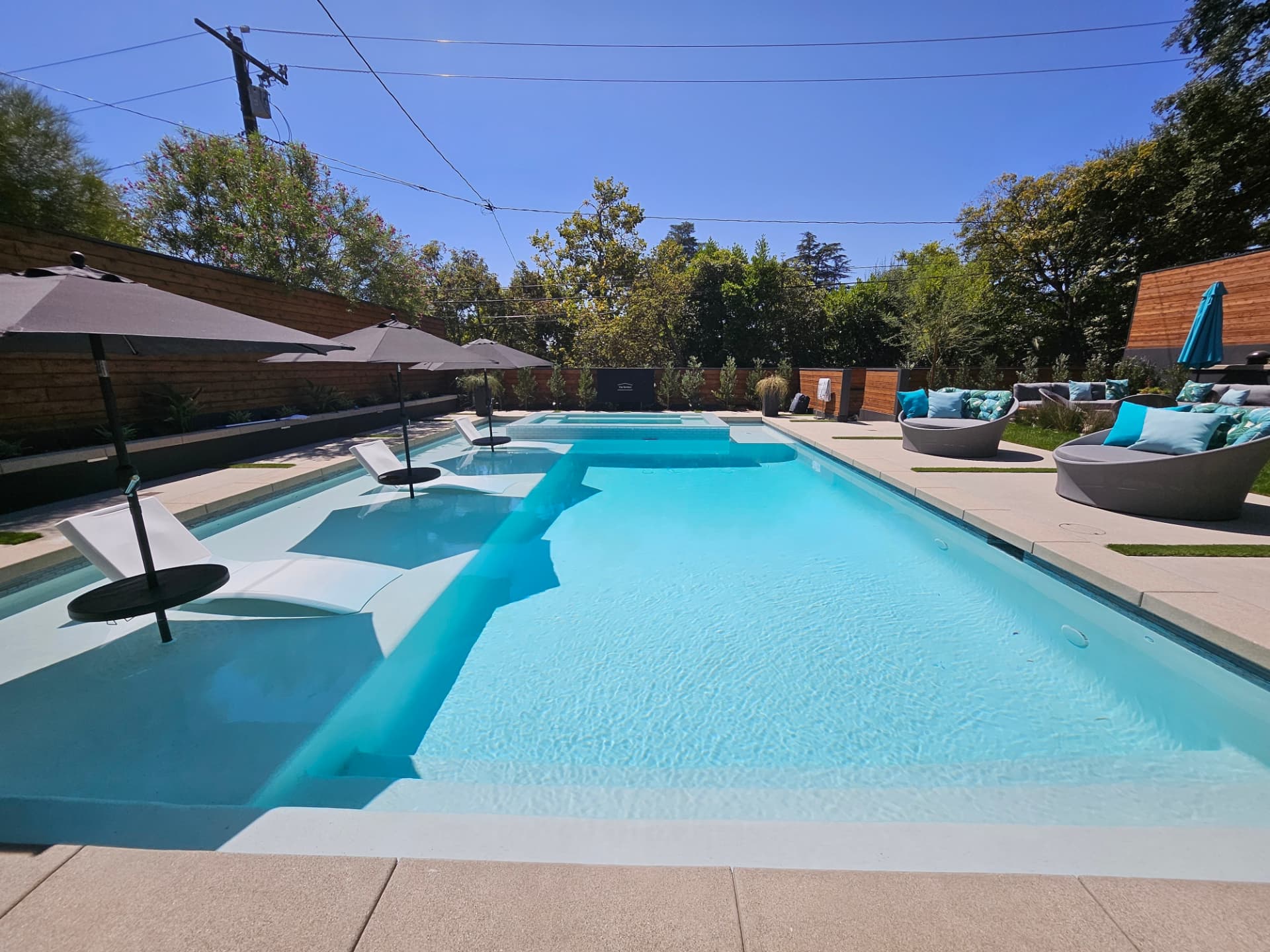Wide modern pool with in water loungers and spa spillway