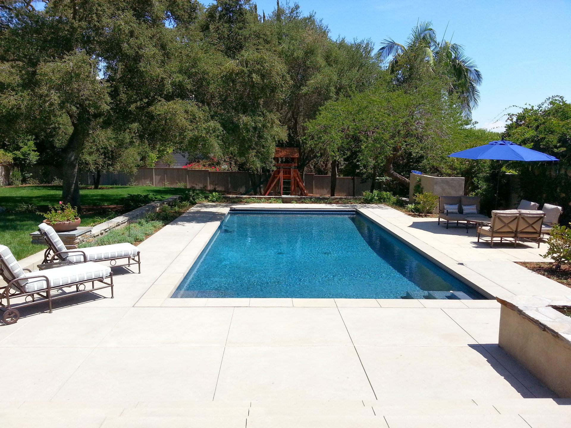 Classic rectangular pool with sun shelf in an oak shaded estate yard